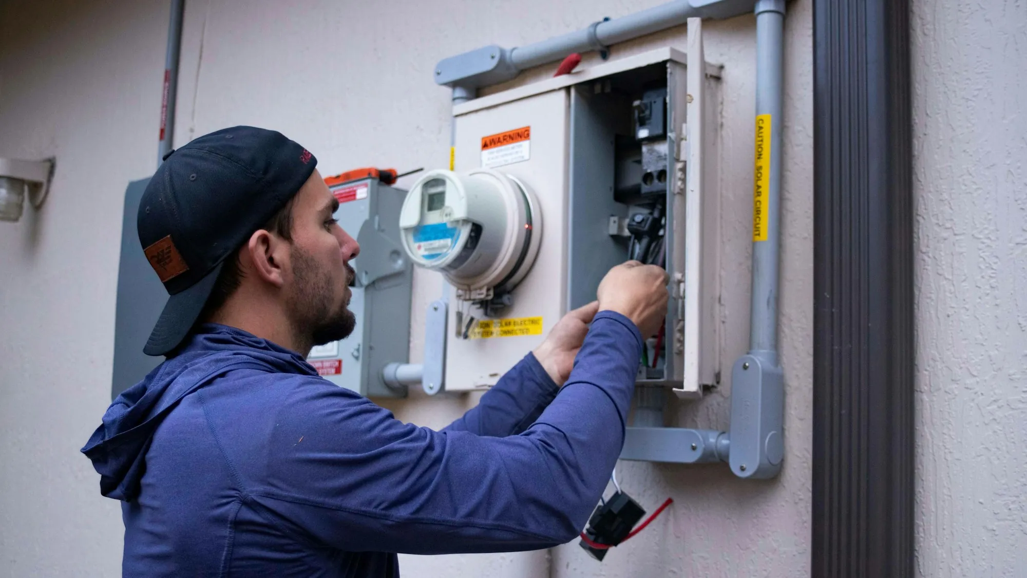 Technician working on a meter and breaker panel outdoors